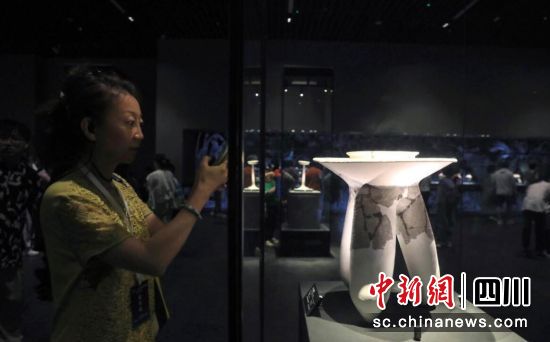 7月1日,一位海外華文媒體代表拍攝展出的商代后期陶三足吹器。記者 王磊 攝 7月1日,一位海外華文媒體代表拍攝展出的商代后期陶三足吹器。記者 王磊 攝